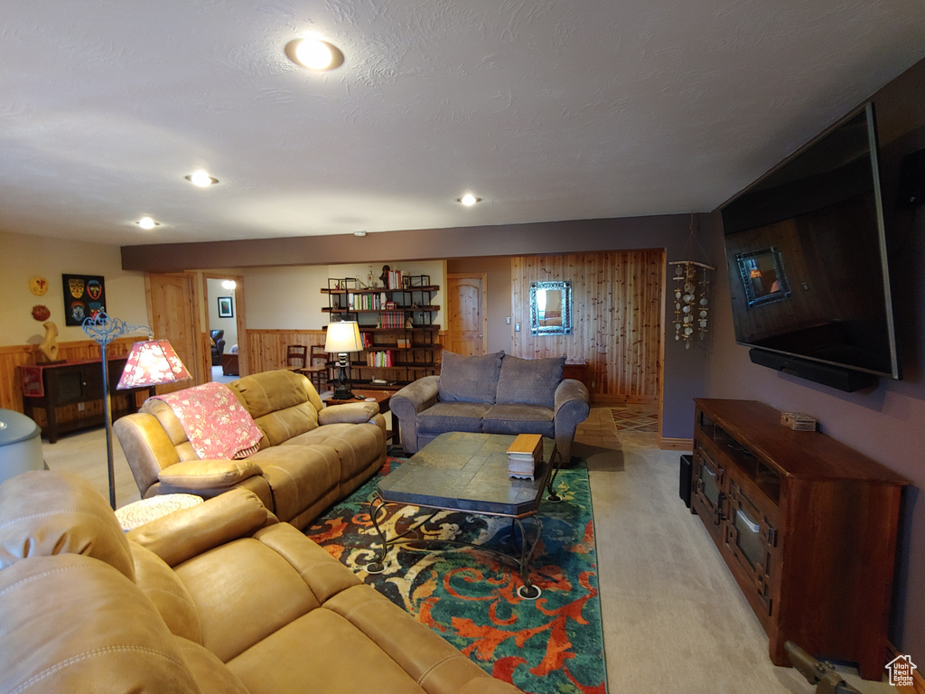 Living area with wooden walls, recessed lighting, light colored carpet, and a wainscoted wall