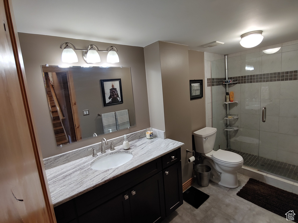 Bathroom featuring tile patterned flooring, vanity, toilet, visible vents, and a stall shower
