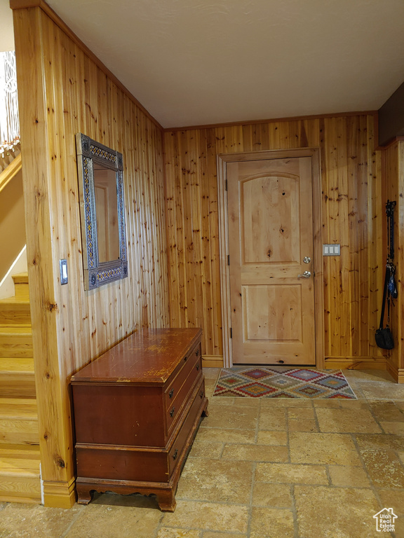Doorway to outside with baseboards, wood walls, and stairway
