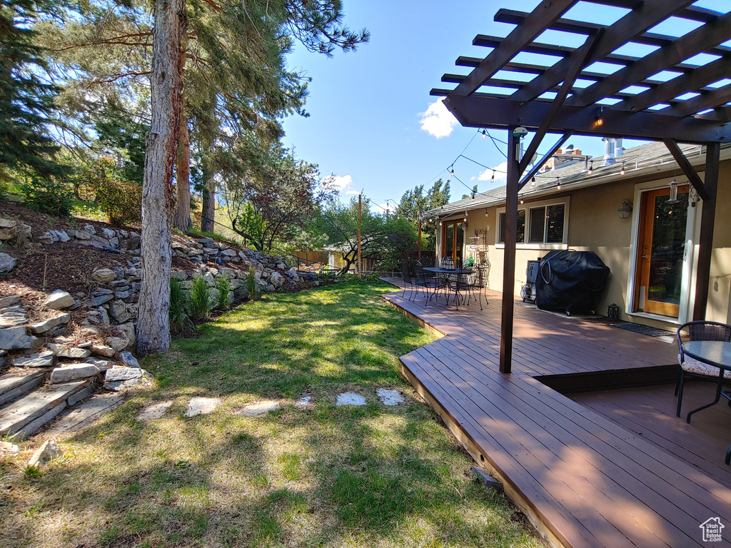 View of yard featuring a pergola, fence, and a wooden deck