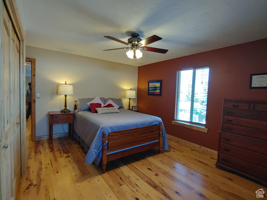 Bedroom with light wood-type flooring, a ceiling fan, and baseboards