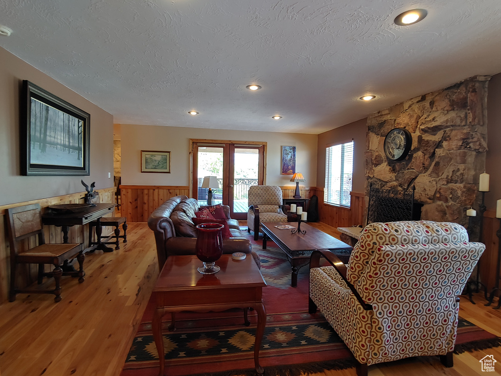 Living room featuring a textured ceiling, wainscoting, wood walls, wood finished floors, and recessed lighting