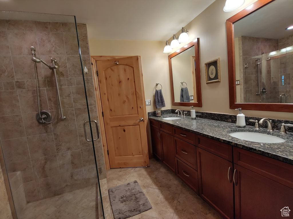 Bathroom featuring a sink, tile patterned floors, a stall shower, and double vanity