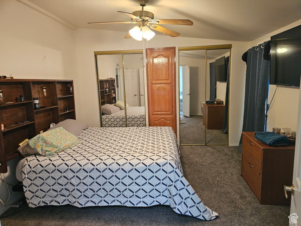 Bedroom with two closets, a ceiling fan, and carpet floors