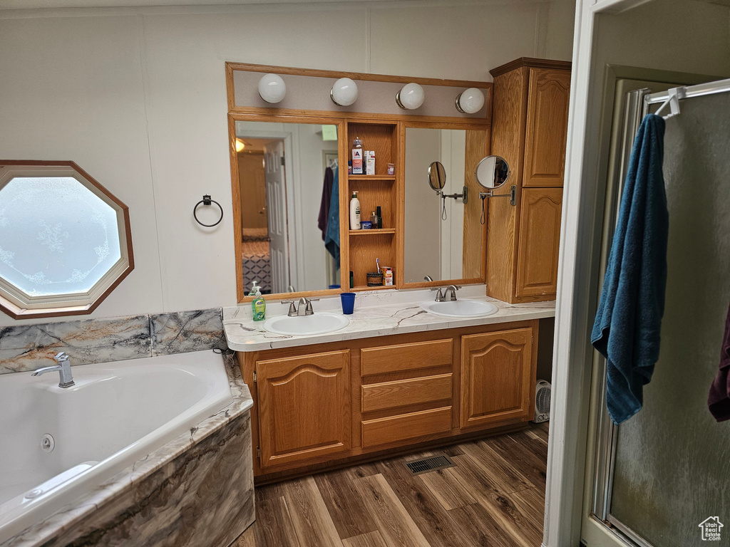 Full bathroom featuring a sink, a stall shower, a tub with jets, and double vanity