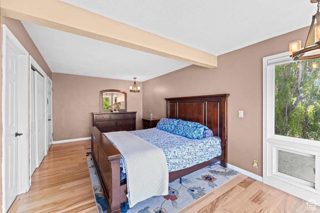 Bedroom with beamed ceiling, baseboards, a chandelier, and light wood finished floors