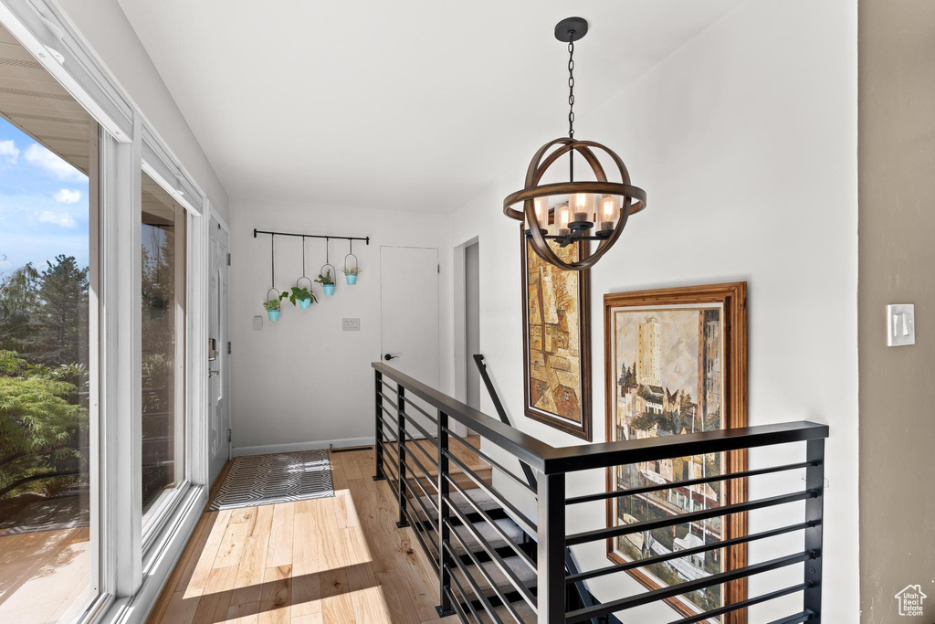 Hallway with baseboards, an upstairs landing, an inviting chandelier, and hardwood / wood-style floors