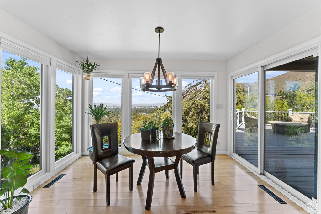 Sunroom / solarium with visible vents, wood finished floors, and a notable chandelier