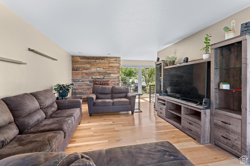 Living room with light wood-type flooring and a stone fireplace
