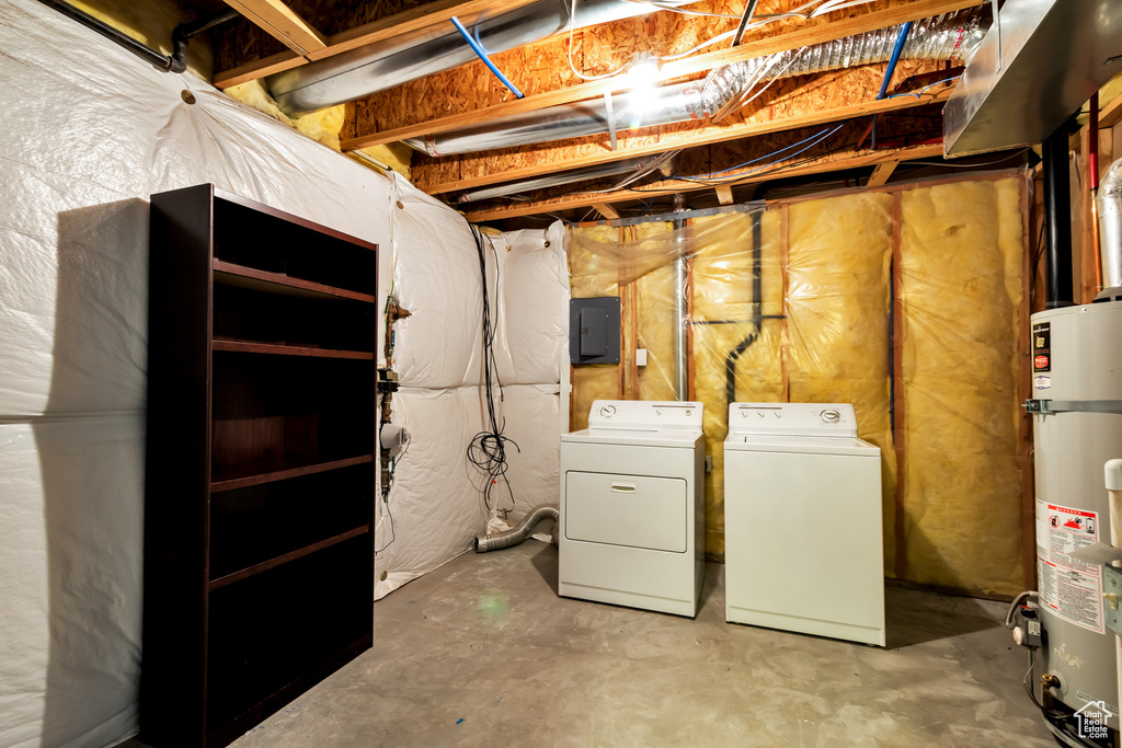 Unfinished basement with washer and clothes dryer, gas water heater, and electric panel