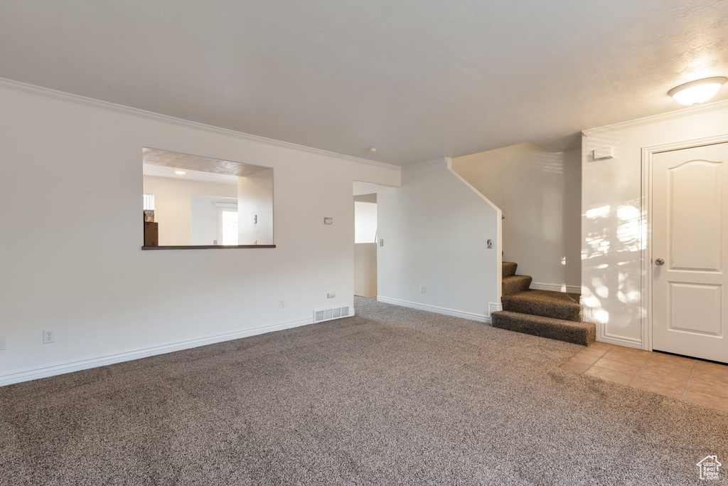Unfurnished living room with crown molding, carpet flooring, and visible vents