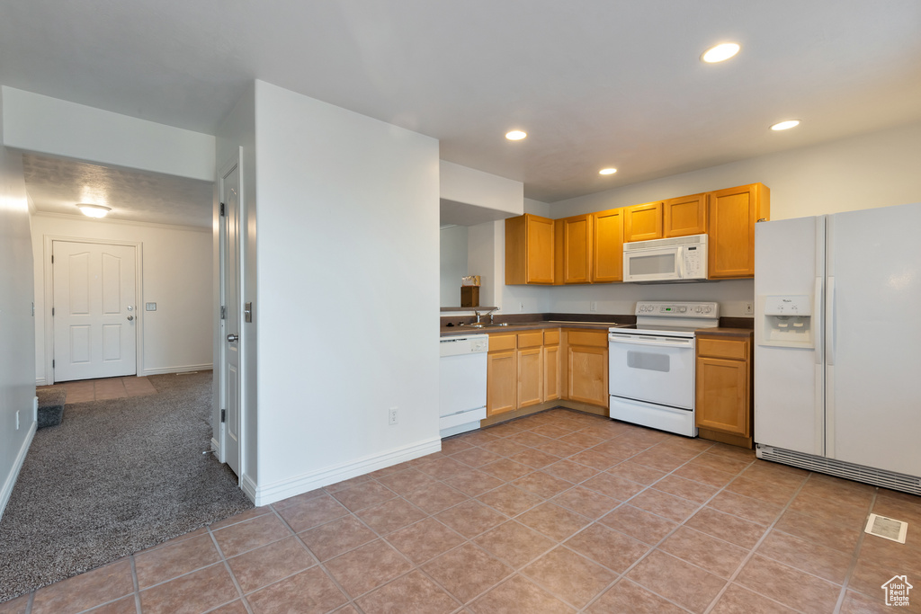 Kitchen featuring dark countertops, baseboards, light tile patterned flooring, recessed lighting, and white appliances