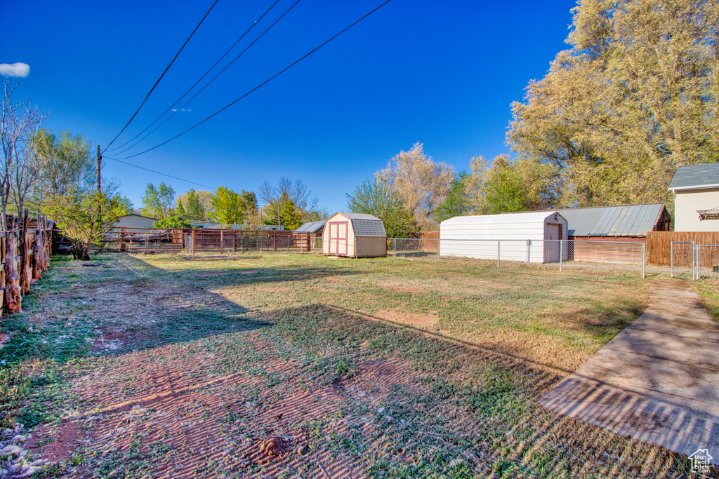 View of yard featuring a fenced backyard, an outdoor structure, and a shed