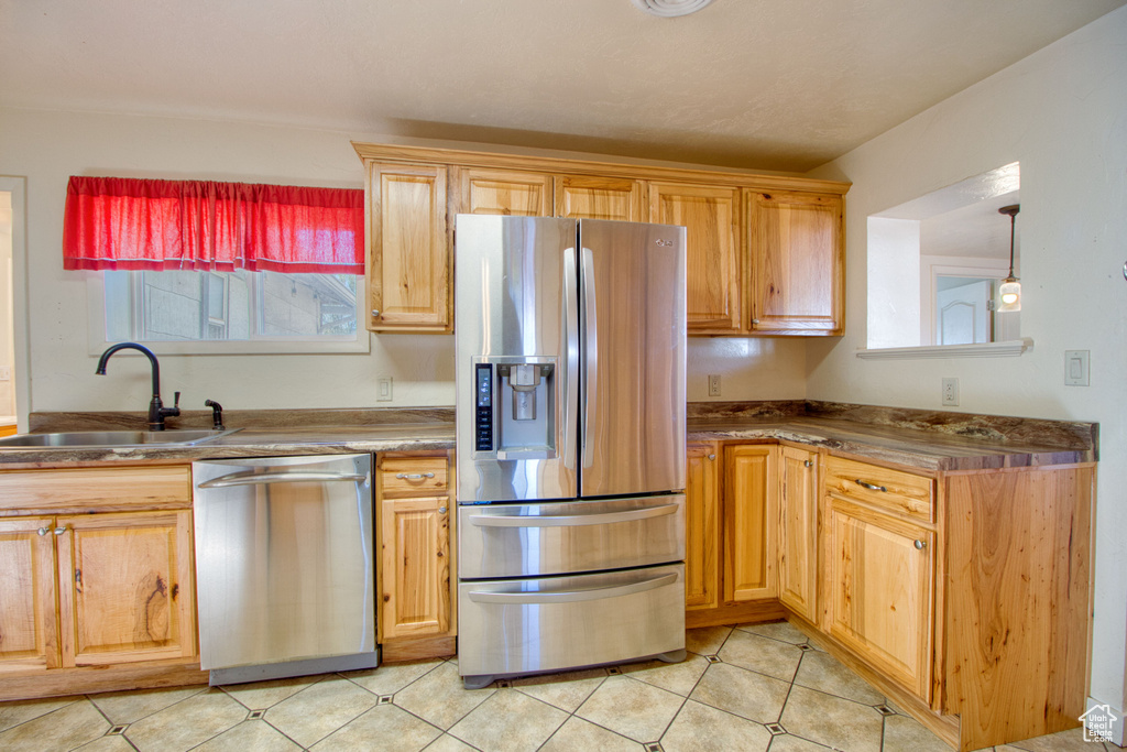 Kitchen featuring a sink, light tile patterned floors, and stainless steel appliances