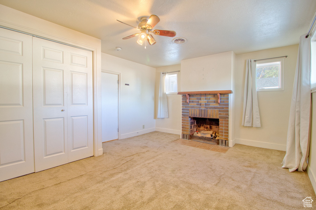 Unfurnished living room featuring a ceiling fan, baseboards, carpet, and a fireplace