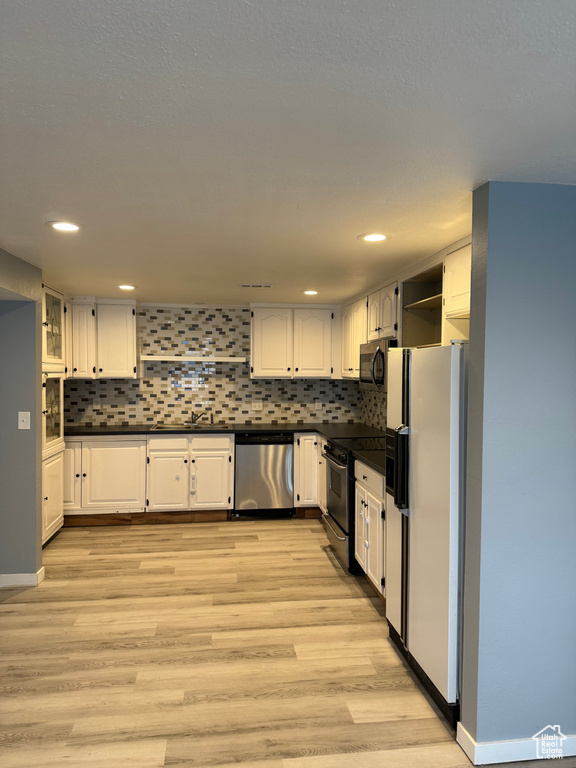 Kitchen with stainless steel dishwasher, open shelves, black microwave, white refrigerator with ice dispenser, and electric stove