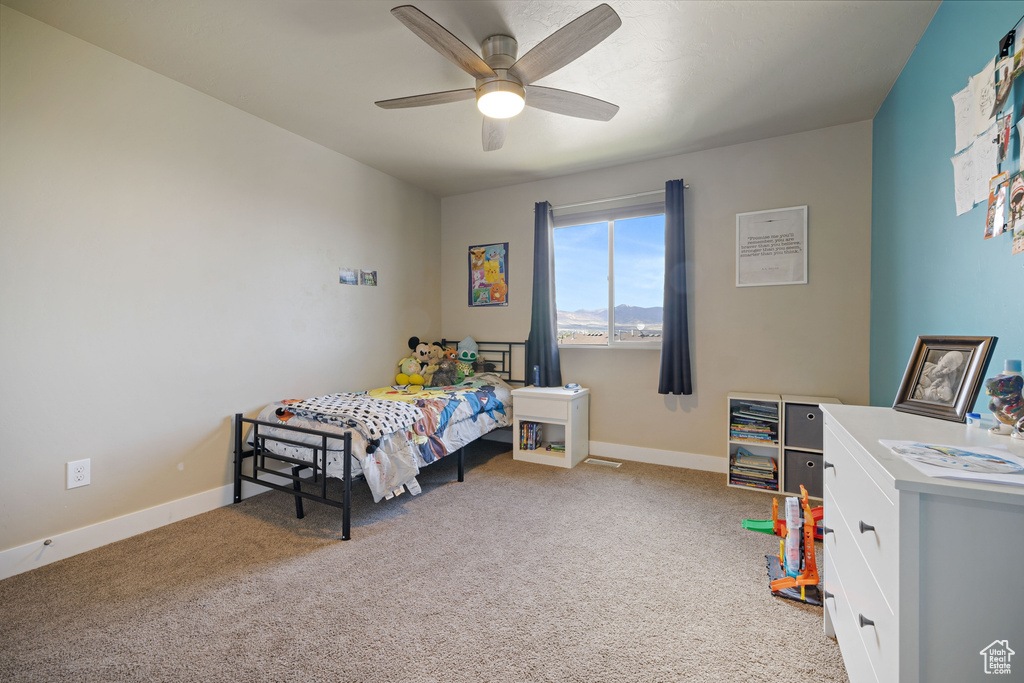 Carpeted bedroom with a ceiling fan and baseboards