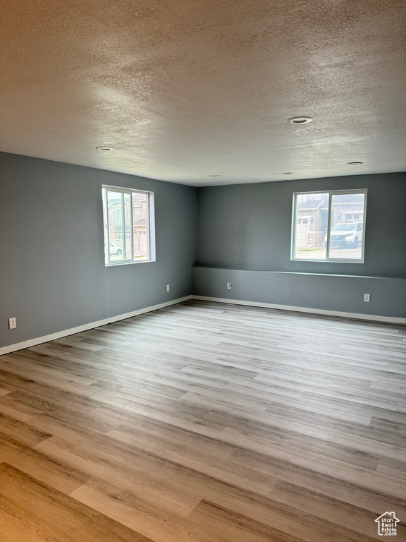 Spare room featuring baseboards, a textured ceiling, and wood finished floors