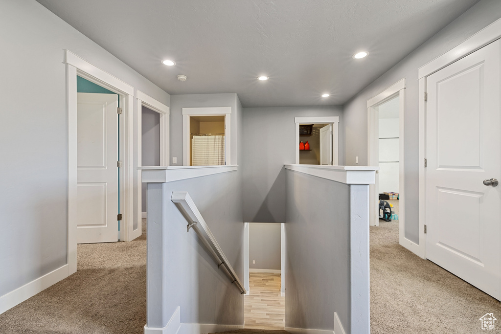 Hallway featuring carpet flooring, recessed lighting, and an upstairs landing