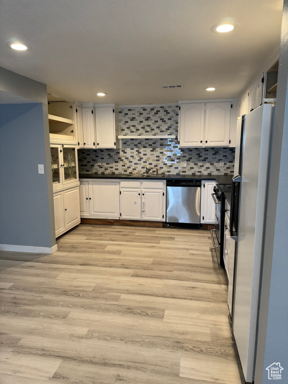 Kitchen featuring dark countertops, stainless steel appliances, white cabinetry, and visible vents