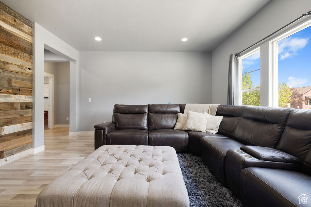 Living room featuring light wood-type flooring, recessed lighting, baseboards, and wooden walls