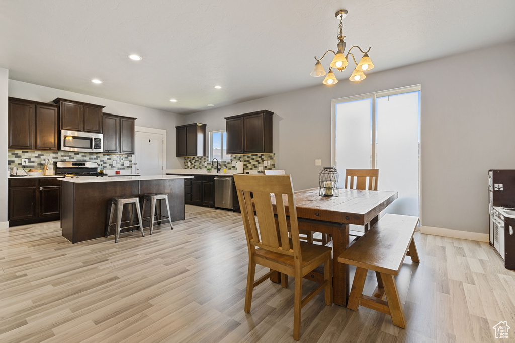Dining space with light wood-style floors, recessed lighting, plenty of natural light, and an inviting chandelier