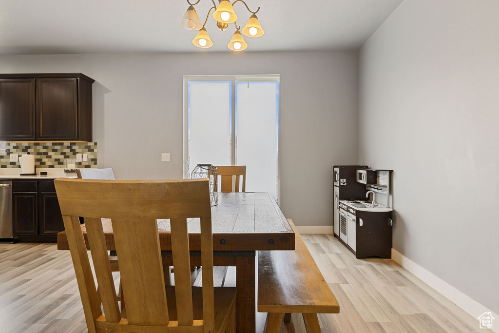 Dining area with light wood-type flooring, baseboards, and a notable chandelier
