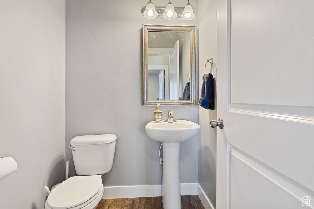 Bathroom featuring toilet, baseboards, and wood finished floors