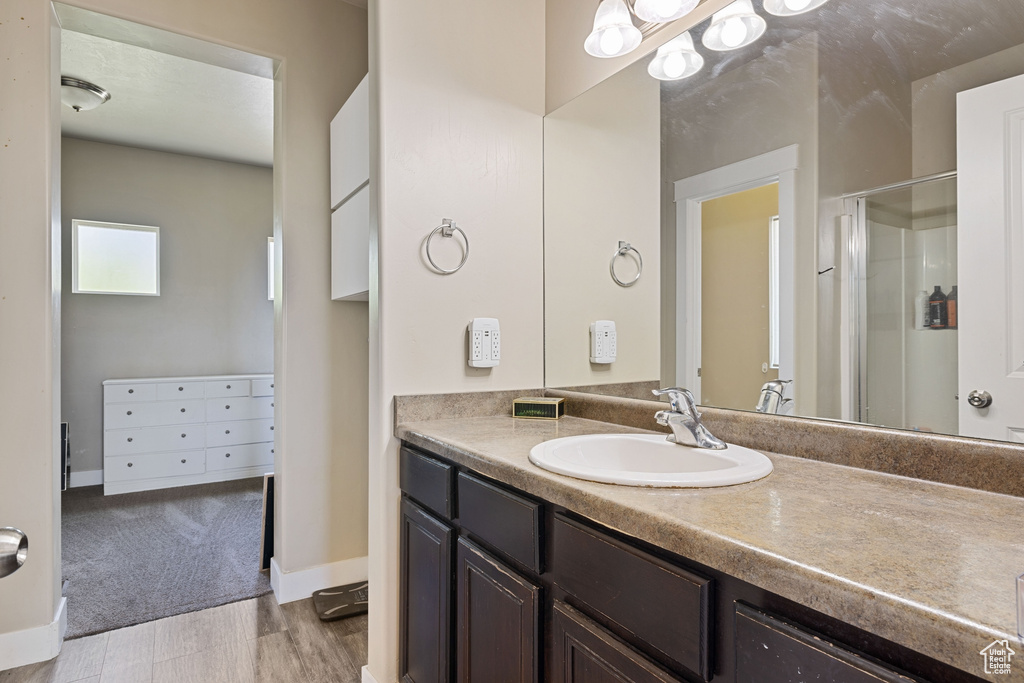 Bathroom with baseboards, a shower stall, wood finished floors, and vanity