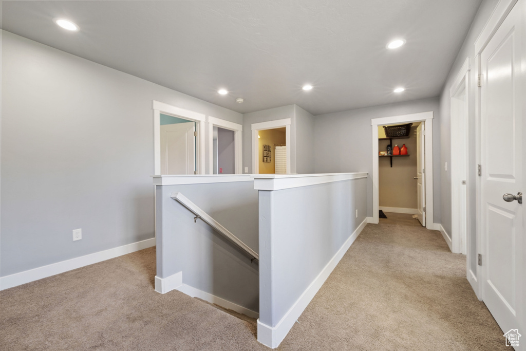 Hall with recessed lighting, an upstairs landing, and light carpet
