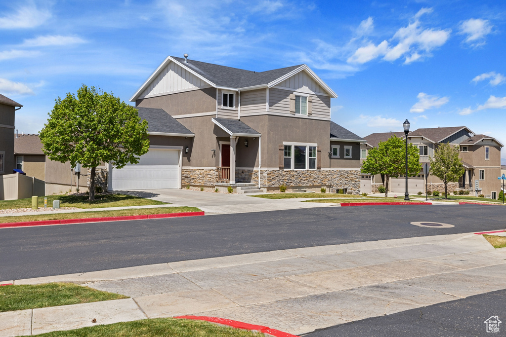 View of front of property featuring a garage, stone siding, stucco siding, concrete driveway, and a residential view