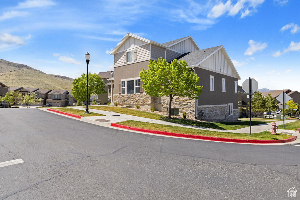 View of front of property featuring board and batten siding, a residential view, a mountain view, and stone siding