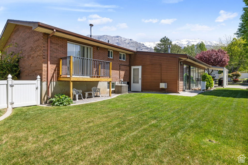 Back of property with a gate, a mountain view, a yard, and brick siding