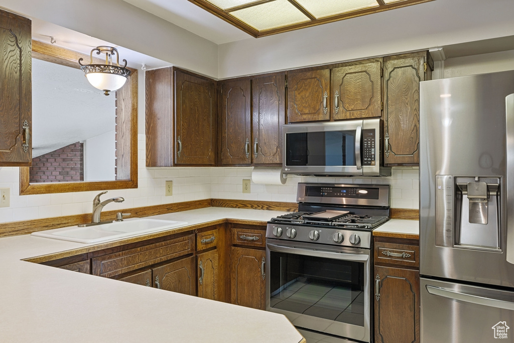 Kitchen with a sink, light countertops, backsplash, and stainless steel appliances
