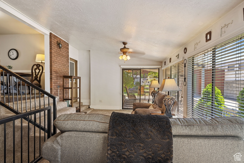 Living room with baseboards, a textured ceiling, ceiling fan, and stairs