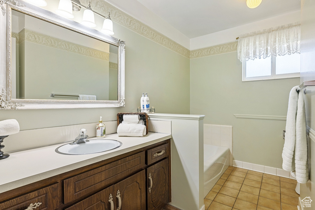 Full bath with vanity, tile patterned flooring, baseboards, and a bath
