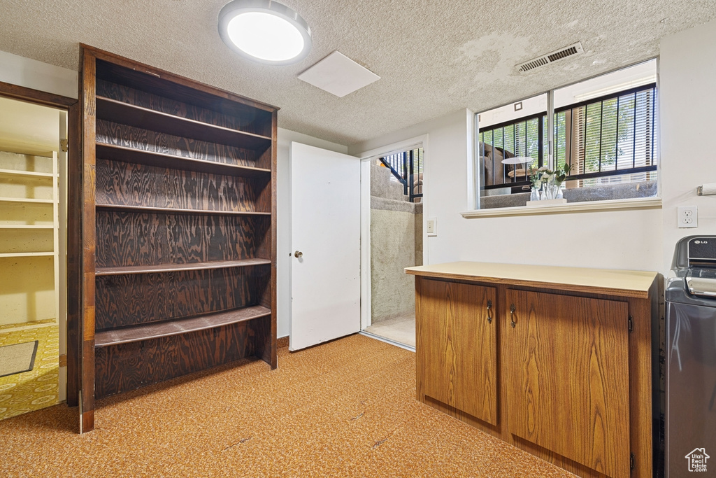 Interior space featuring light colored carpet, a textured ceiling, and visible vents