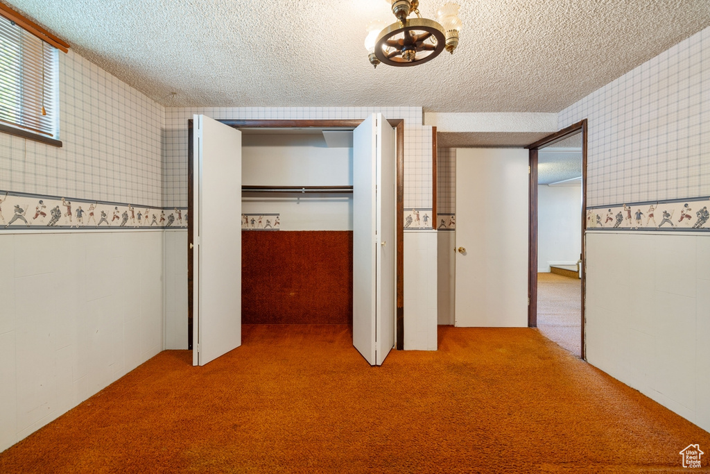 Unfurnished bedroom with a closet, a textured ceiling, and carpet
