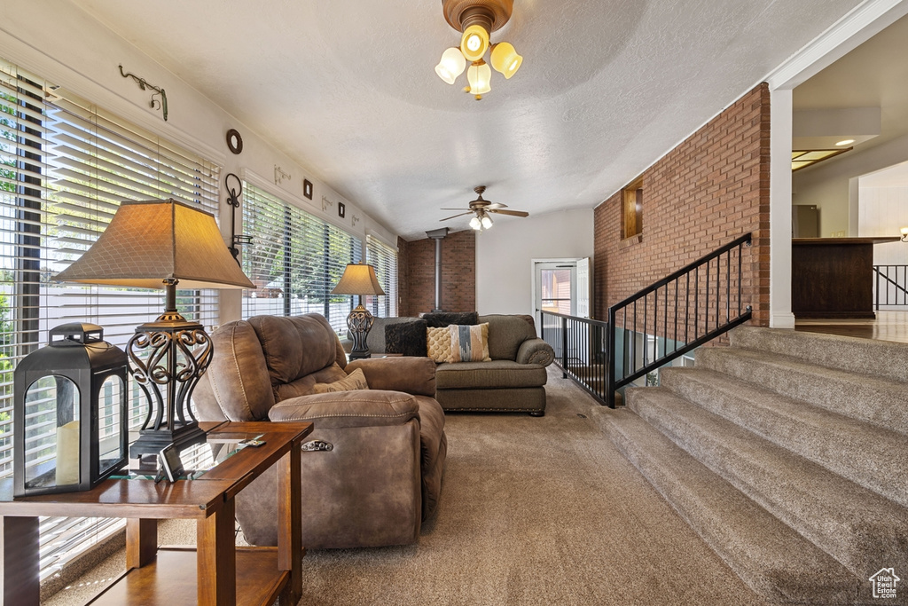 Living room featuring carpet floors, a ceiling fan, stairs, and vaulted ceiling