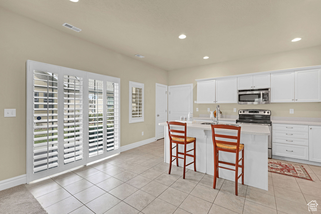 Kitchen with a kitchen island with sink, visible vents, appliances with stainless steel finishes, light countertops, and recessed lighting