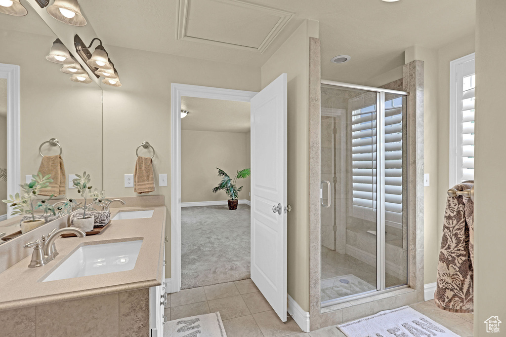 Bathroom with a sink, tile patterned flooring, a shower stall, and double vanity