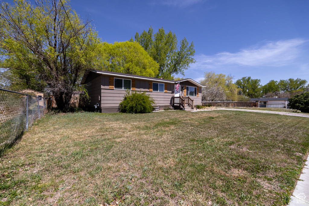 Ranch-style house with fence and a front lawn