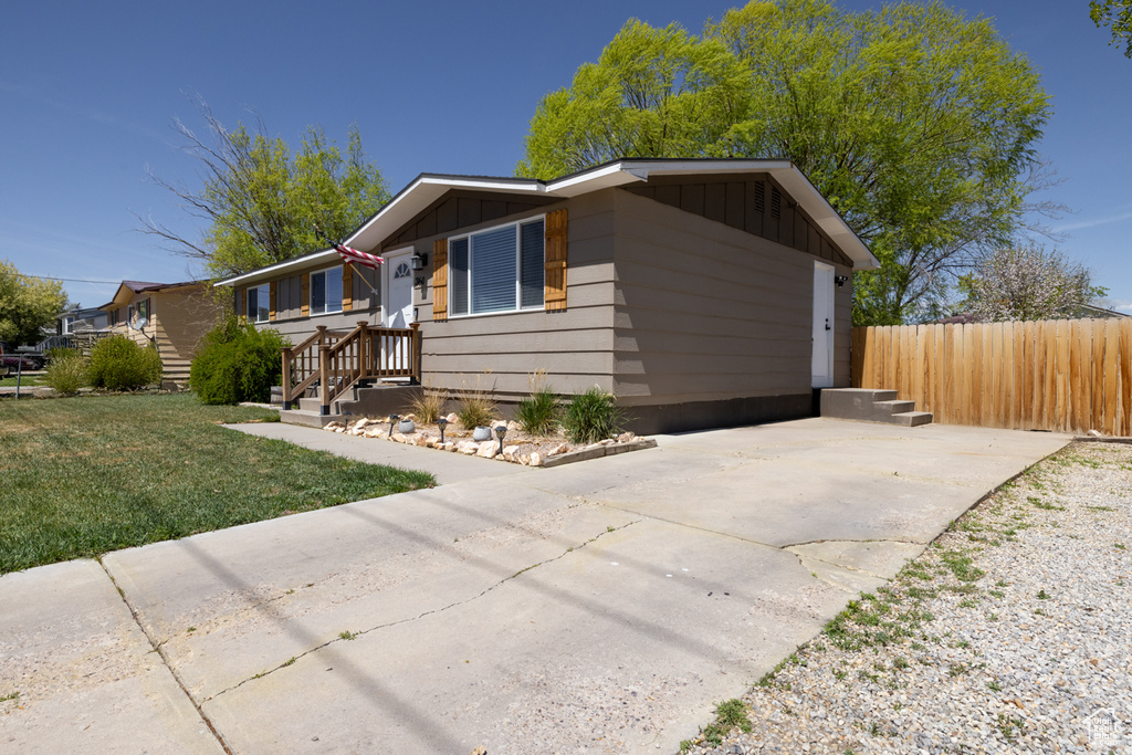 Ranch-style home featuring fence, board and batten siding, concrete driveway, and a front yard