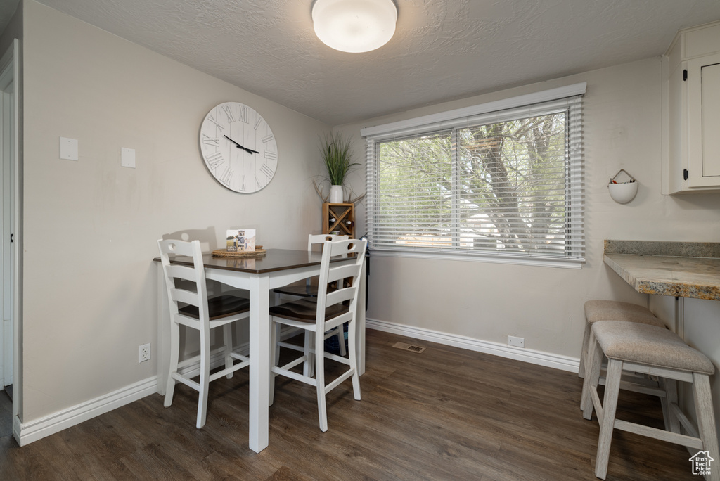 Dining room with dark wood-style flooring, baseboards, visible vents, and a textured ceiling