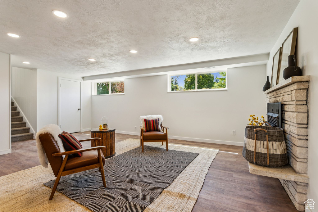 Living area featuring plenty of natural light, baseboards, wood finished floors, and a stone fireplace
