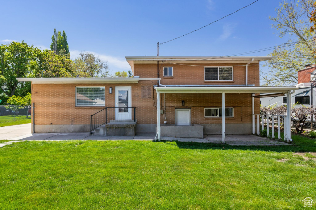 Back of property featuring fence, a yard, a patio area, and brick siding