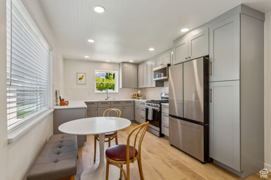 Kitchen featuring gray cabinets, tasteful backsplash, light wood-type flooring, stainless steel appliances, and recessed lighting