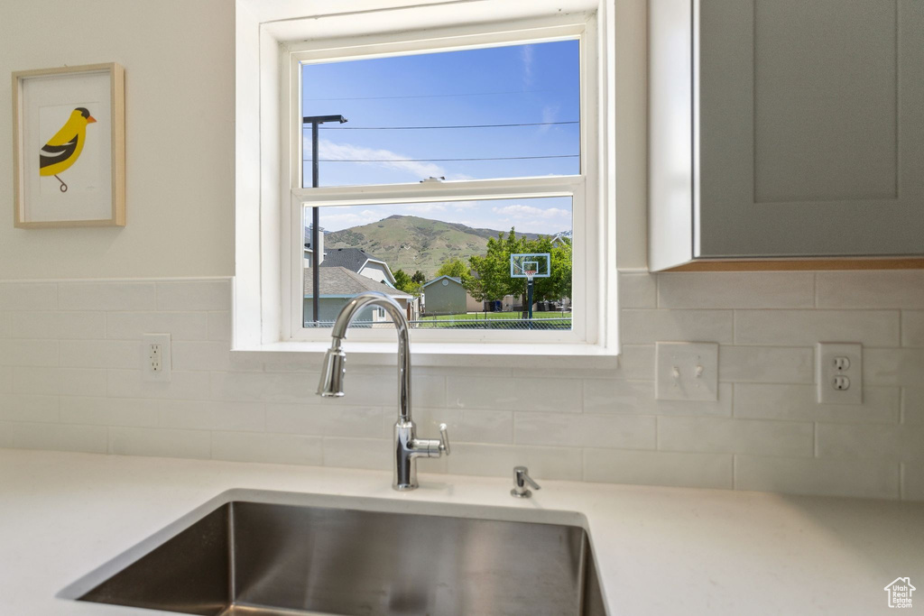 Interior details featuring light countertops, a mountain view, a sink, and tasteful backsplash