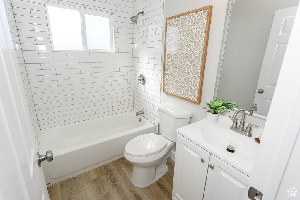 Full bath with vanity, toilet, wood finished floors, and shower / tub combination