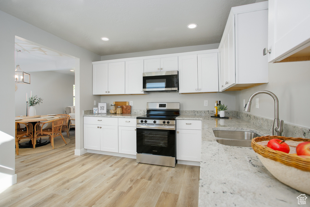 Kitchen featuring light wood-type flooring, a sink, appliances with stainless steel finishes, and white cabinets
